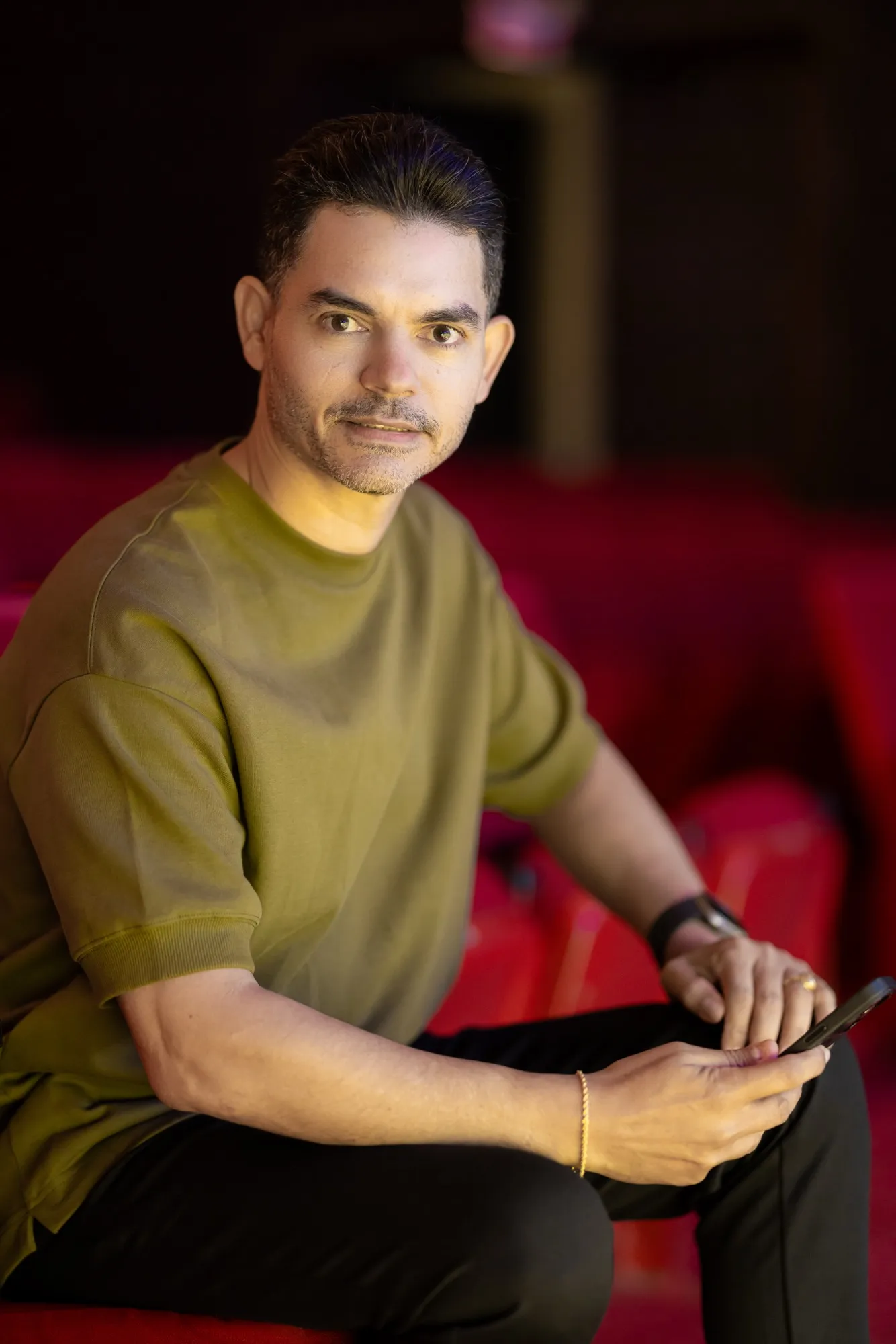 Primer plano de Camilo Then con una tableta, sentado en el teatro