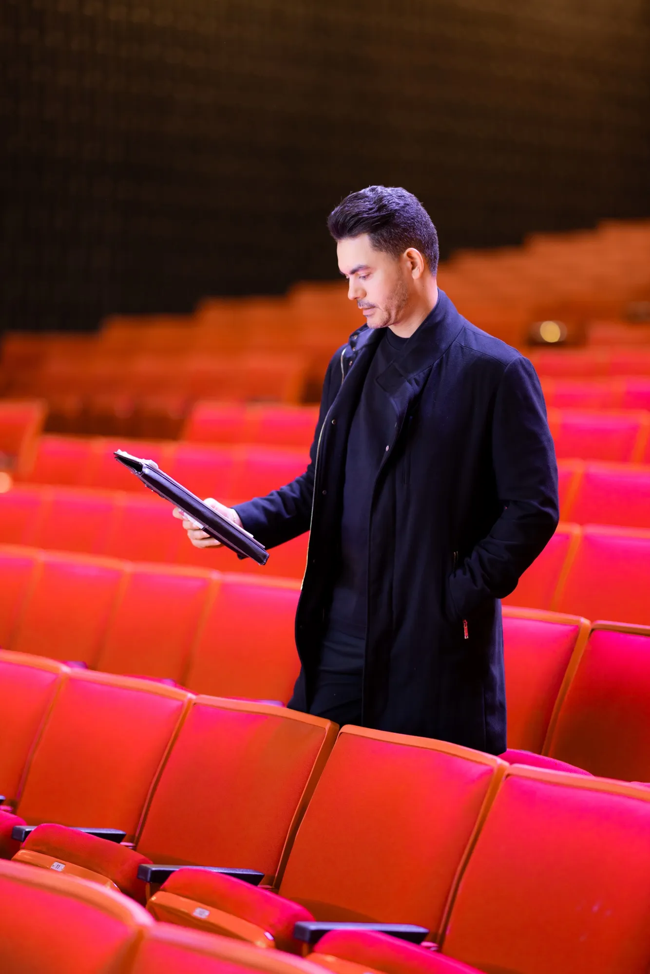 Camilo Then consulta la tableta en la platea del teatro